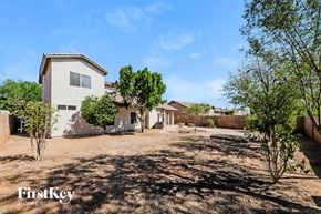 Surprise house for rent - A house with a brown roof and a white wall is surrounded by trees and grass.