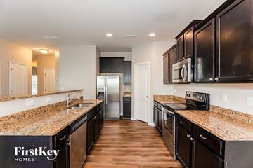 Dallas house for rent - A kitchen with dark brown cabinets and a granite countertop.