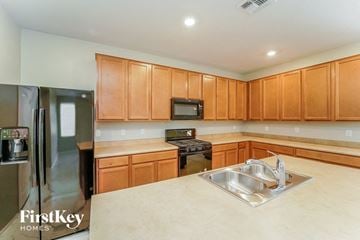 Tucson house for rent - a kitchen with wooden cabinets and stainless steel appliances