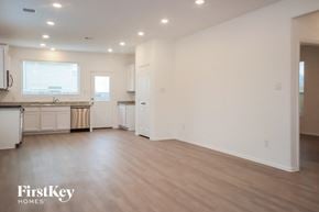 New Caney house for rent - A spacious kitchen and living room with white walls and wooden floors.