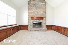 Edmond house for rent - an empty living room with a brick fireplace and a window