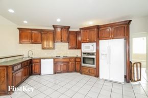 Edmond house for rent - a large kitchen with wooden cabinets and white appliances