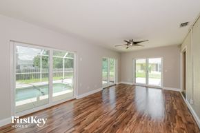 North Port house for rent - A spacious room with wooden floors and a ceiling fan.