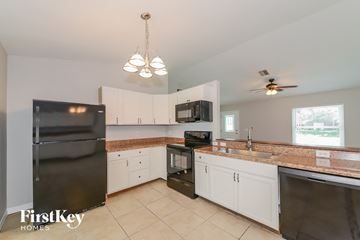North Port house for rent - A kitchen with a black fridge, microwave, and stove top oven.
