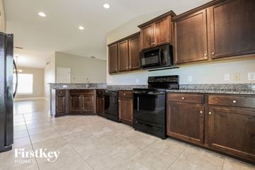 Punta Gorda house for rent - a kitchen with dark wood cabinets and black appliances