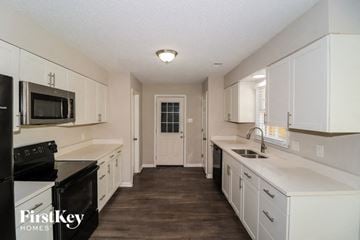 Memphis house for rent - A kitchen with white cabinets and black appliances.