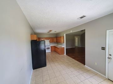 Deridder house for rent - A kitchen with a black fridge and brown cabinets.