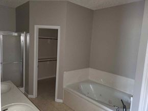 Deridder house for rent - A white bathtub is in a bathroom with a walk-in shower.