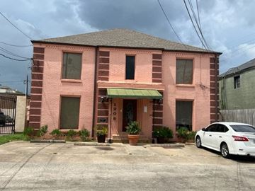 Houston apartment for rent - a pink brick building with a white car parked in front