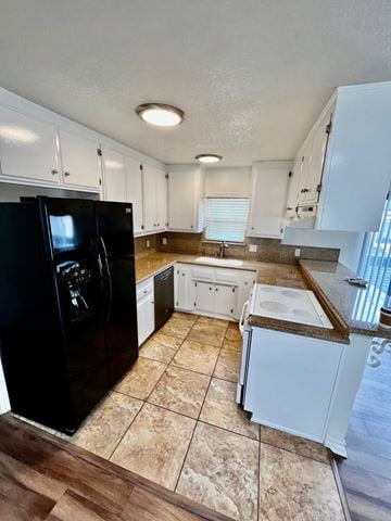 Seal Beach apartment for rent - A black refrigerator is in a kitchen with white cabinets.
