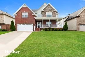 Clarksville house for rent - a brick house with a white garage door and a lawn