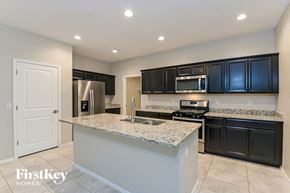 Tucson house for rent - a kitchen with black cabinets and a granite counter top