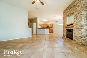 Tucson house for rent - A spacious living room with a stone fireplace and a kitchen in the background.