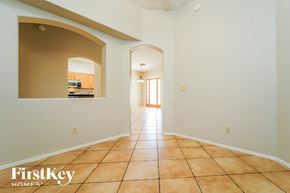 Tucson house for rent - A hallway with a tile floor and a view of a kitchen through an arched doorway.