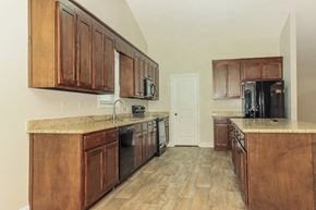 Statham house for rent - a kitchen with wooden cabinets and appliances and a door