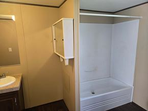 Shawnee house for rent - A white shower stall is in a bathroom with a sink and mirror.