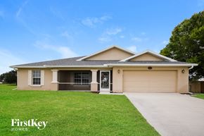 Cape Coral house for rent - a beige house with a lawn and a driveway