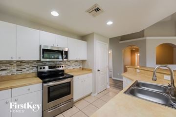 Cape Coral house for rent - a kitchen with stainless steel appliances and white cabinets