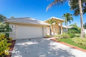 Port St. Lucie house for rent - A house with a driveway and palm trees in front.