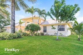 Port St. Lucie house for rent - A house with a white exterior and a palm tree in front.