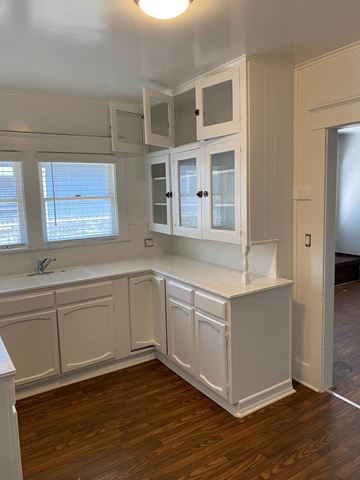 Long Beach apartment for rent - a kitchen with white cabinets and a wooden floor