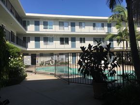 Long Beach apartment for rent - A pool is surrounded by a black fence and a building with balconies.