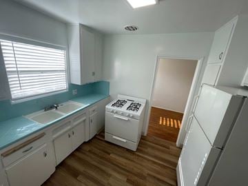 Long Beach apartment for rent - A kitchen with white cabinets and a white fridge.