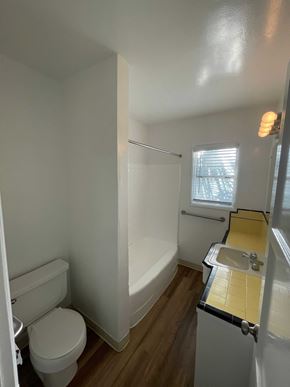 Long Beach apartment for rent - A white toilet sits in a small bathroom with a white tub and sink.