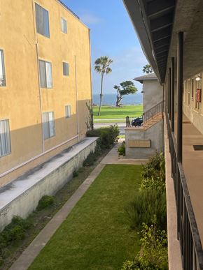 Long Beach apartment for rent - A yellow building with a balcony overlooking a green lawn.