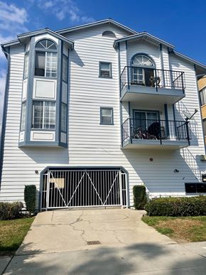 Long Beach apartment for rent - A white two-story apartment building with a black gate in front.