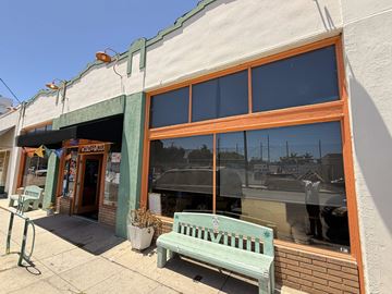 Long Beach apartment for rent - A green bench is in front of a building with a glass window.