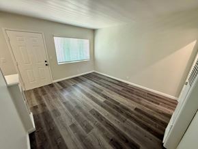 Long Beach apartment for rent - A room with a wooden floor and a window with blinds.