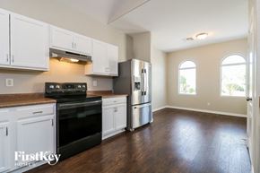 Buckeye house for rent - an empty kitchen with white cabinets and a black stove and refrigerator