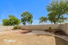 Buckeye house for rent - a backyard with gravel and trees and a retaining wall