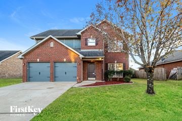 Bessemer house for rent - a brick house with blue garage doors and a tree