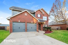 Bessemer house for rent - a brick home with blue garage doors in front of a green driveway