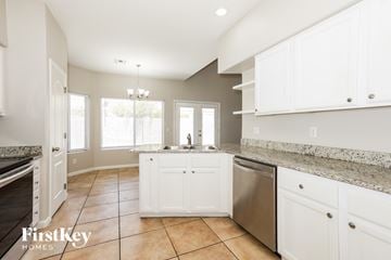 Mesa house for rent - A kitchen with white cabinets and a marble countertop.