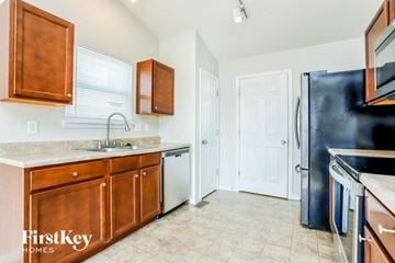 Wentzville house for rent - a kitchen with wooden cabinets and a black refrigerator