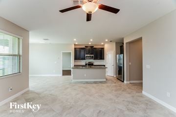 Ruskin house for rent - A spacious living room with a kitchen in the background and a ceiling fan above.