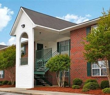 Rocky Mount apartment for rent - A red brick house with a white front porch and a green staircase.