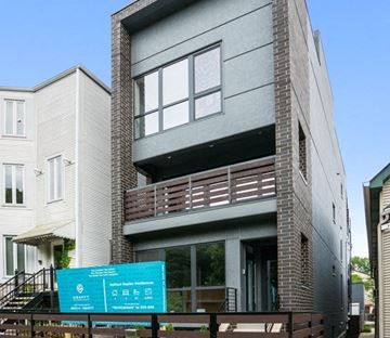Chicago apartment for rent - A modern two-story building with a balcony and a sign in front.