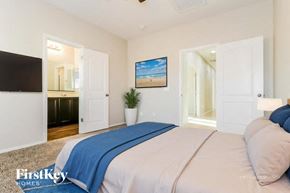 Buckeye house for rent - A bedroom with a bed, a television, and a painting of a beach scene on the wall.