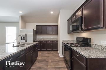 Spring house for rent - A kitchen with dark brown cabinets and granite countertops.
