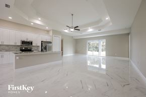 Lehigh Acres house for rent - an empty kitchen and living room with a ceiling fan