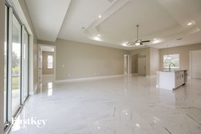 Lehigh Acres house for rent - an empty living room with a kitchen and a ceiling fan