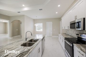 Lehigh Acres house for rent - a large kitchen with marble counter tops and white cabinets