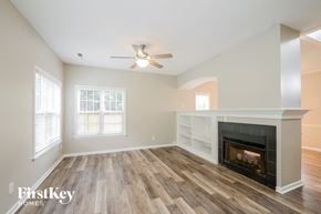 King house for rent - A spacious room with a fireplace and a ceiling fan.