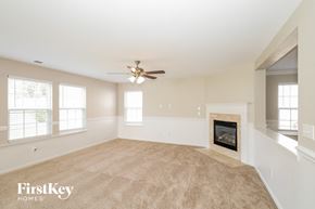 Gastonia house for rent - a living room with a fireplace and a ceiling fan