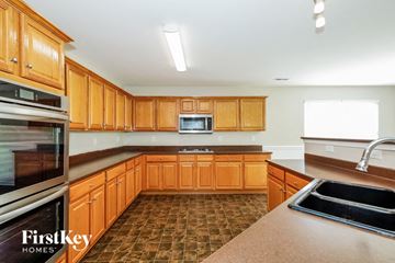 Gastonia house for rent - a kitchen with wooden cabinets and stainless steel appliances