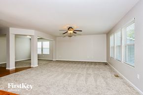 Wentzville house for rent - A spacious room with a ceiling fan and carpeted floor.